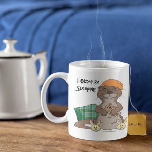 Steaming I Otter Be Sleeping mug with a tea bag beside a teapot on a wooden table