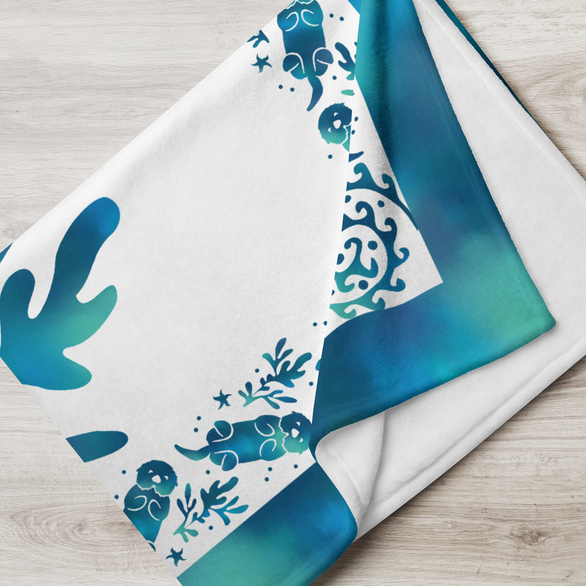 Sea Otter Tie-dye Throw Blanket-60x80-lifestyle-2 | Otter Things Close-up of a folded Sea Otter Tie-Dye throw with blue tie-dye border and kelp