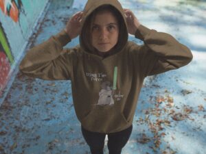 Young woman wearing brown I Otter Be Using the Force Hoodie