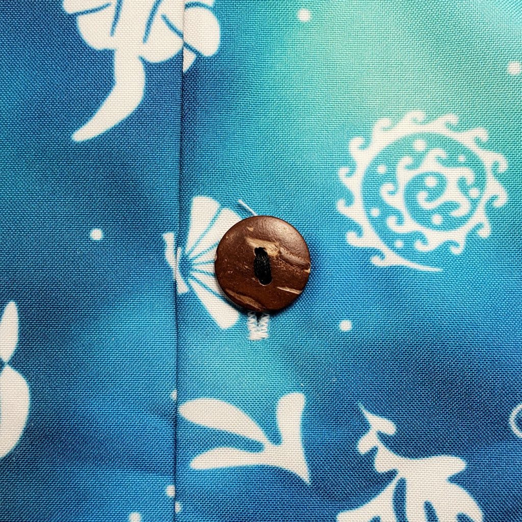 Close-up of a coconut-style button on the Sea Otter Tie-Dye Hawaiian shirt's print